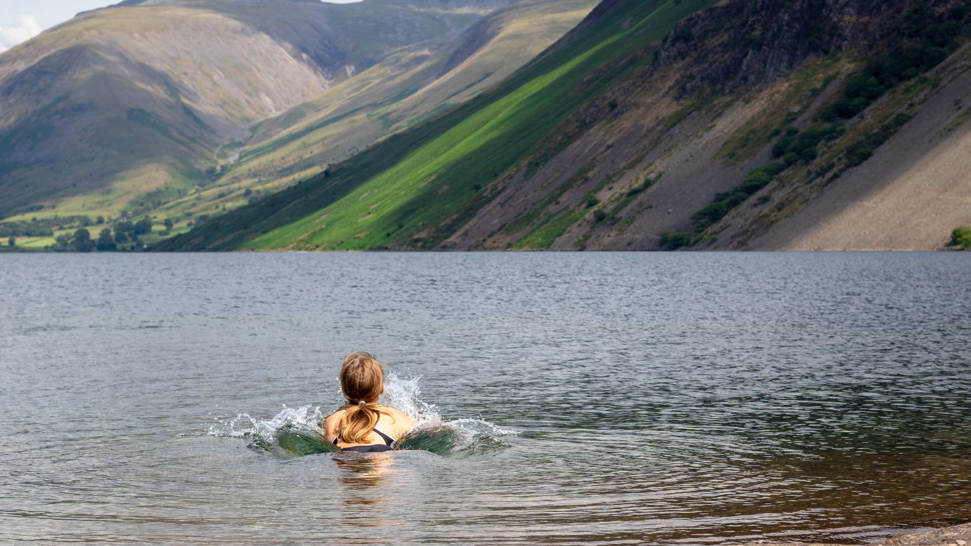 young woman swimming in scenic lake 